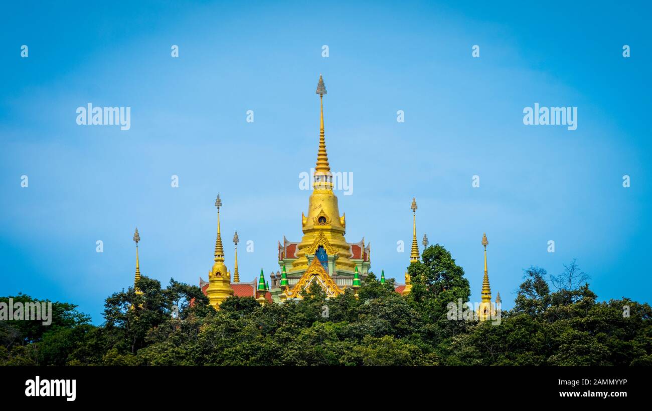 Temple thaïlandais s'élevant au-dessus des arbres avec ciel bleu clair dans Ben Krut Thaïlande Banque D'Images