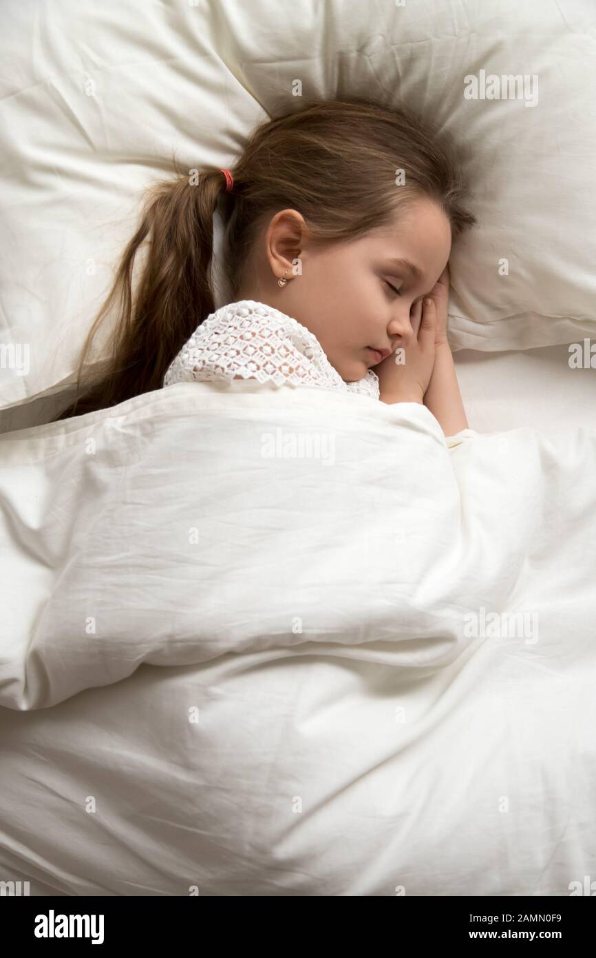 Enfant calme, petite fille dormant dans un lit confortable photo verticale Banque D'Images