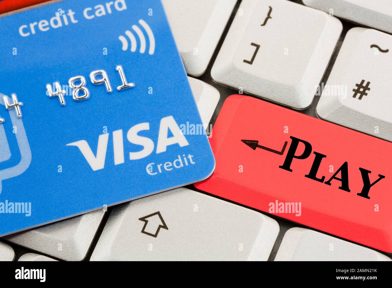 Carte de crédit Visa sur un clavier avec le mot Play écrit sur une touche  rouge pour illustrer le paiement pour le jeu de Paris en ligne concept.  Angleterre Royaume-Uni Grande-Bretagne Photo