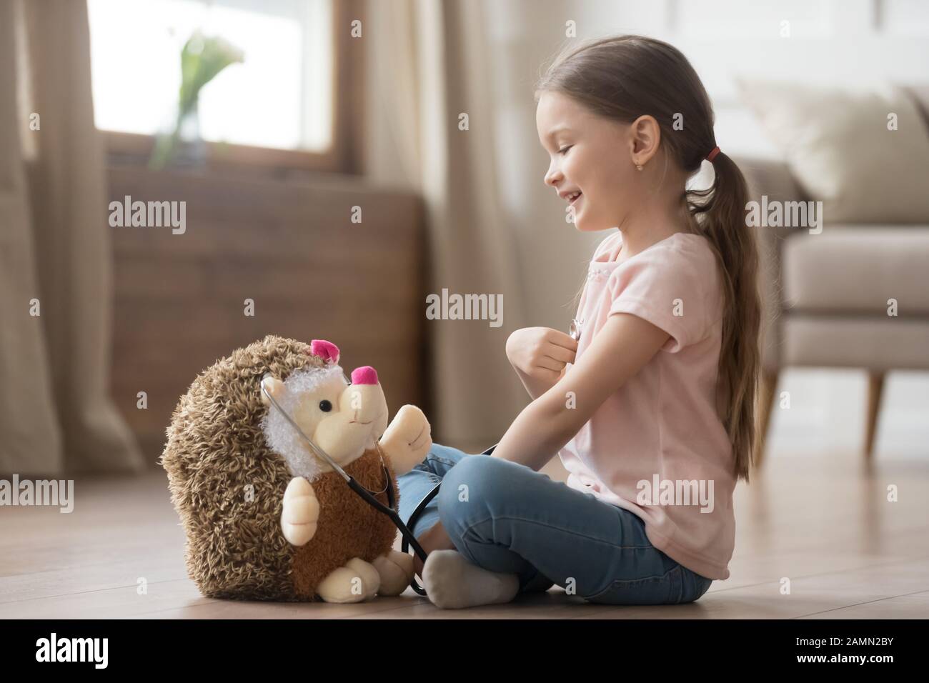 Jolie petite fille jouant médecin avec jouet et stéthoscope Banque D'Images