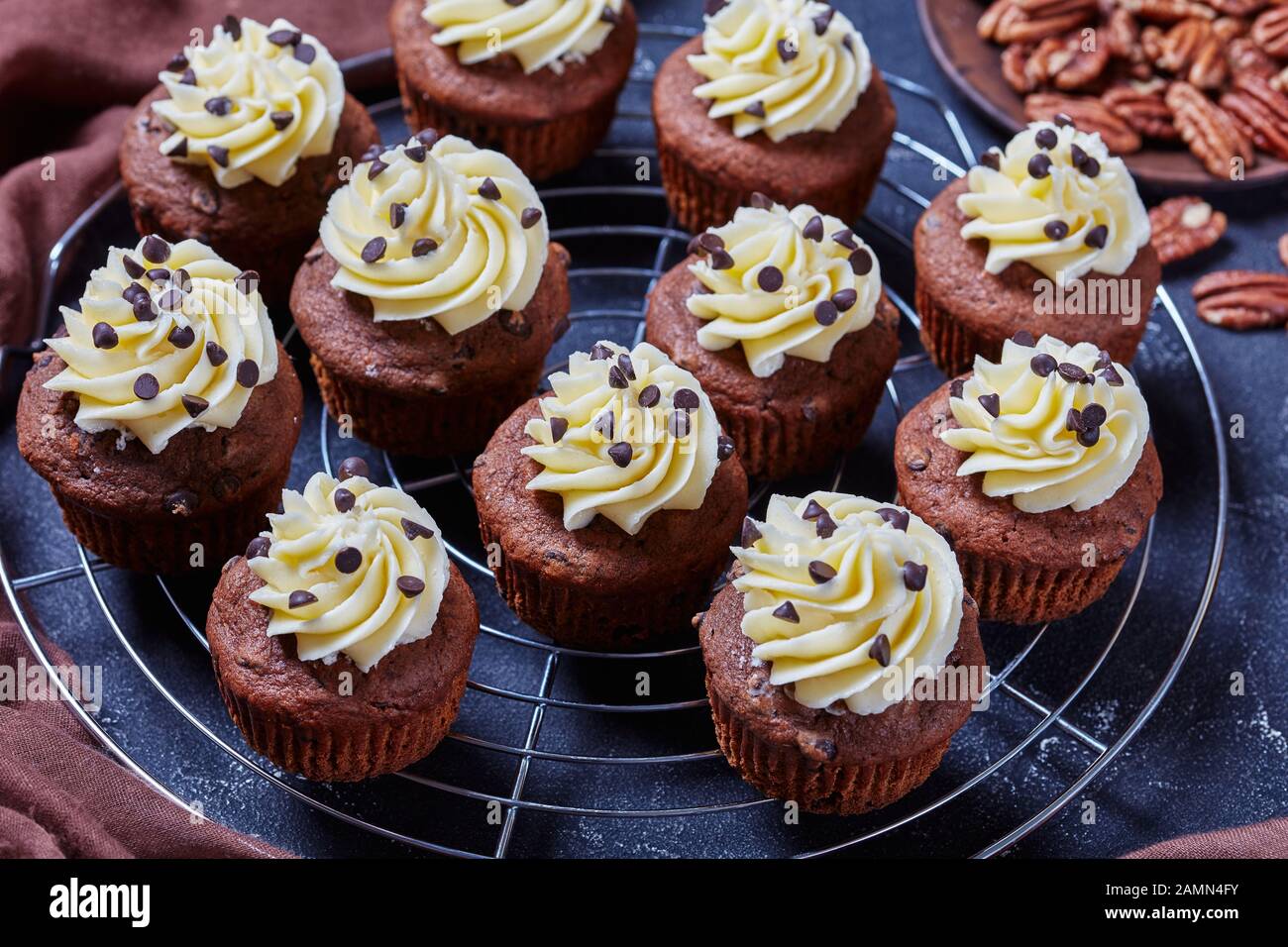 Cupcakes au chocolat recouverts de crème au beurre givrant sur un porte-gâteaux en métal sur une table en béton, vue horizontale de dessus Banque D'Images