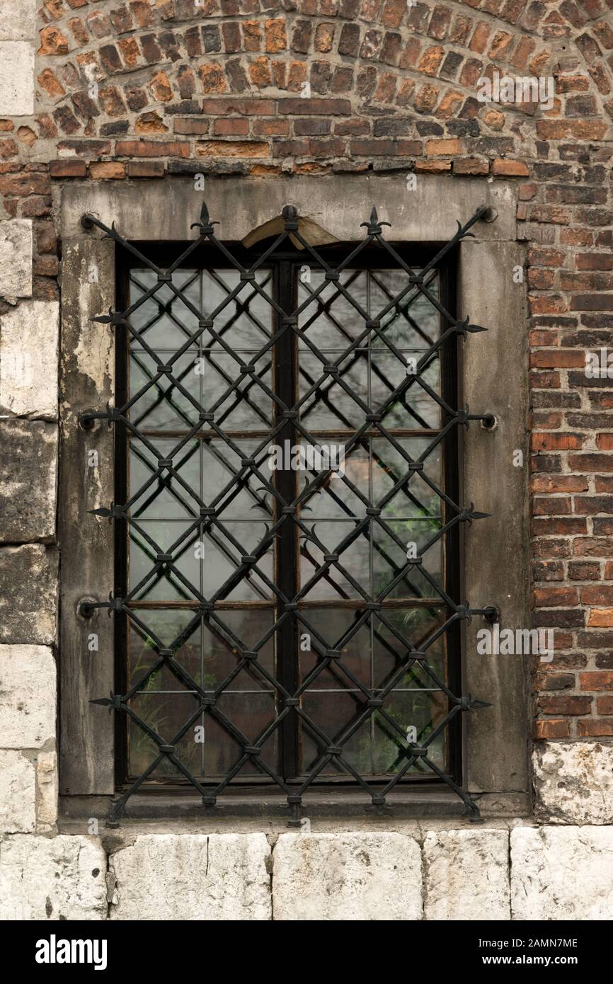 Fenêtre avec grille métallique sur l'ancien bâtiment en brique dans le quartier juif Kazimierz de Cracovie, Pologne Banque D'Images
