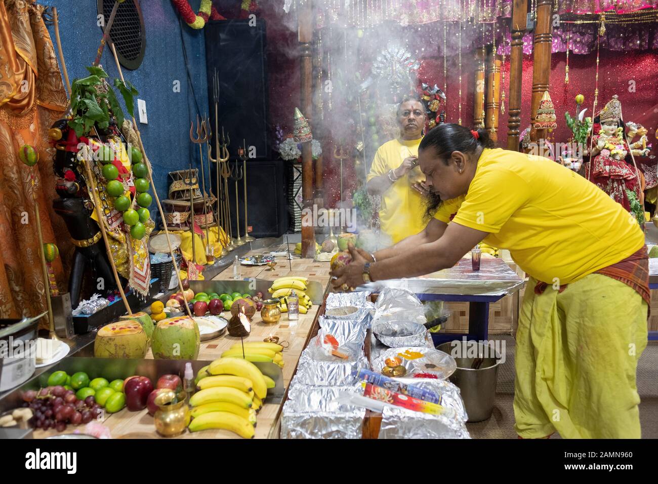 Un prêtre hindou fait une offrande de noix de coco aux divinités comme c'est une coutume dans l'hindouisme. Dans un temple en Jamaïque, Queens, New York City. Banque D'Images