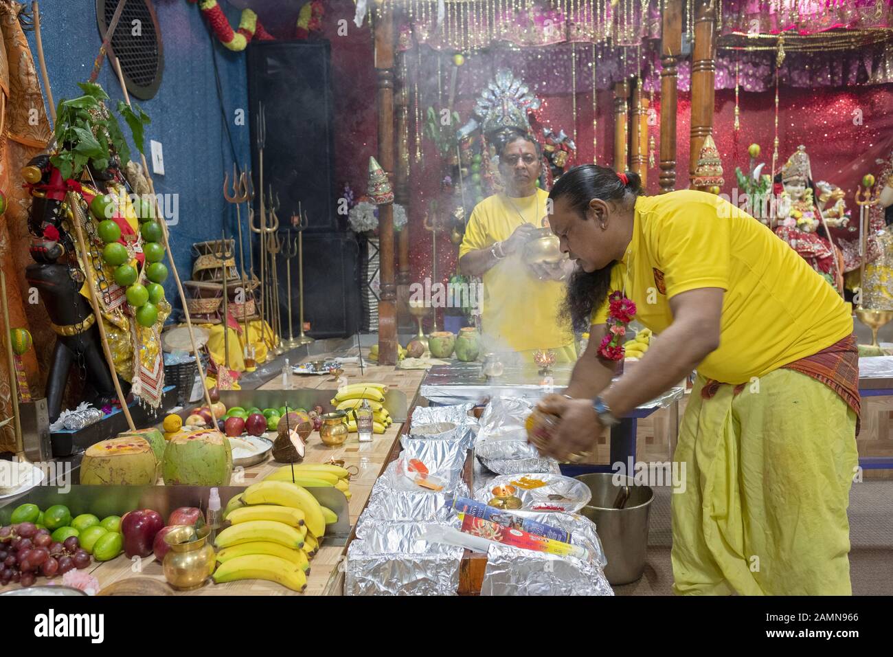 Un prêtre hindou fait une offrande de noix de coco aux divinités comme c'est une coutume dans l'hindouisme. Dans un temple en Jamaïque, Queens, New York City. Banque D'Images
