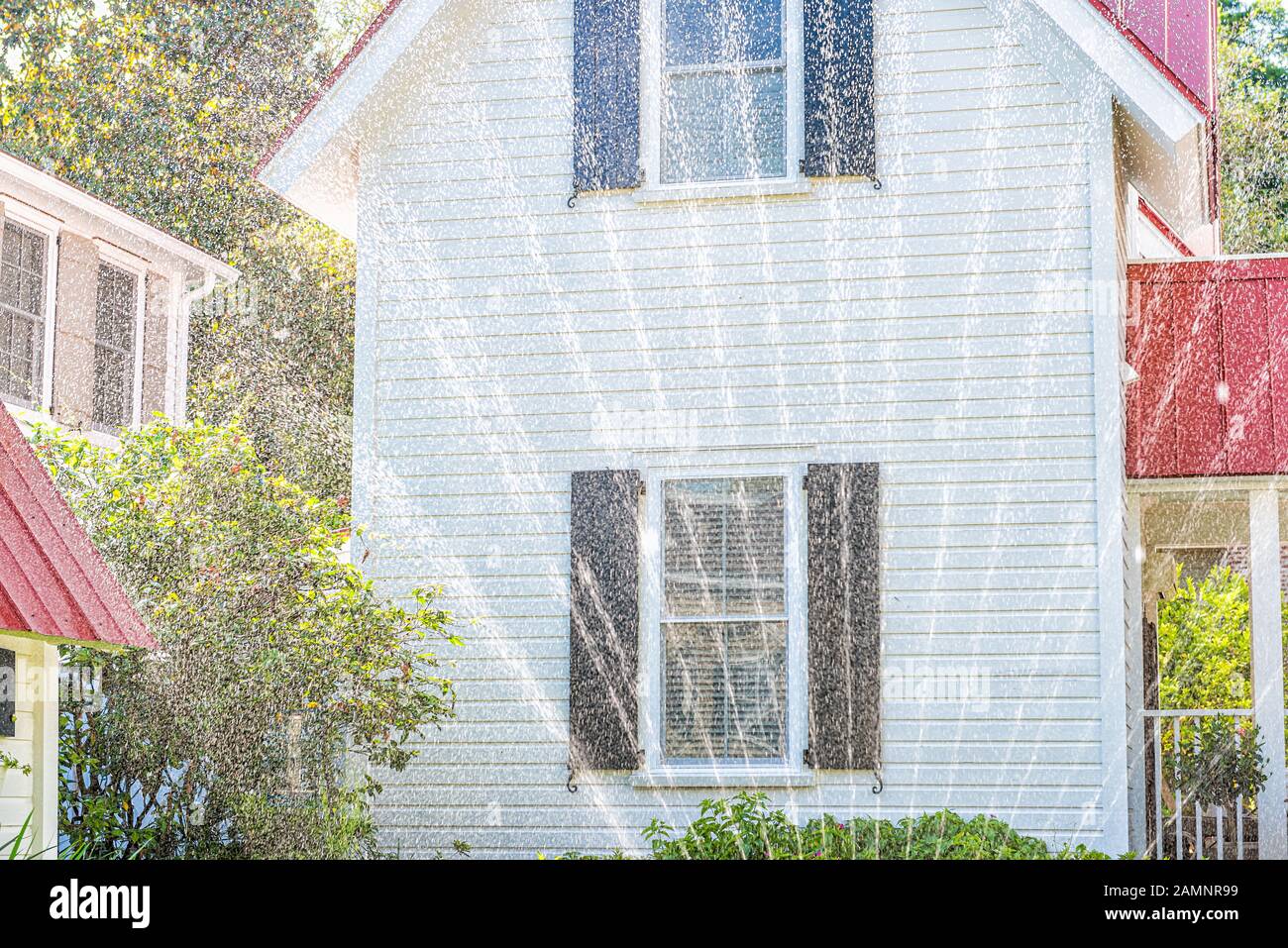 Bâtiment résidentiel américain typique à Charleston, région de Caroline du Sud avec architecture blanche et rouge et arroseurs arroseurs goutte d'eau de pelouse Banque D'Images
