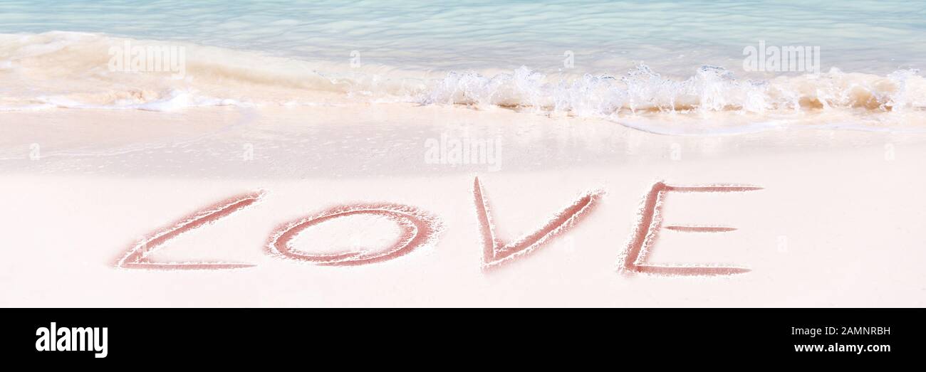Amour écrit sur le sable blanc d'une plage idyllique, bannière panoramique de Saint Valentin Banque D'Images