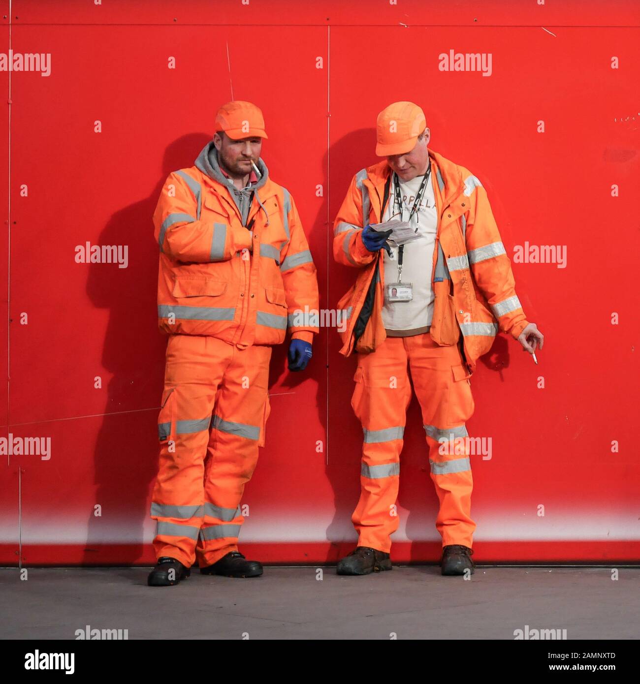 Les travailleurs de la construction. Une paire de vêtus de couleurs vives les travailleurs manuels en prenant une pause-cigarette à partir de leur travail. Banque D'Images