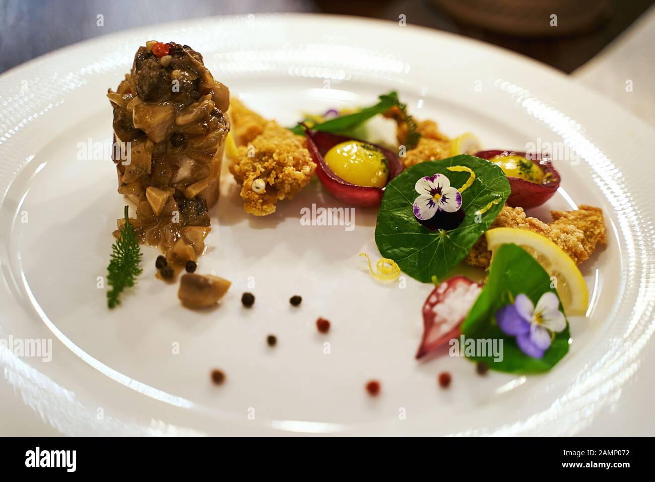 Concept de haute cuisine ou de haute cuisine. Pattes de grenouille et moelle osseuse servies avec sauce et fleurs violettes brutes comestibles. Délicieux repas exclusif. Banque D'Images