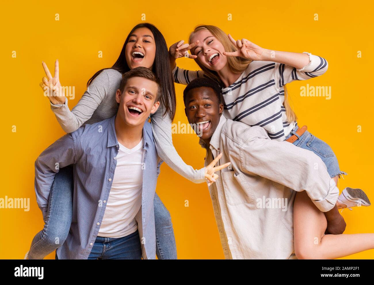 Deux couples internationaux pour adolescents qui s'amusent sur fond jaune Banque D'Images