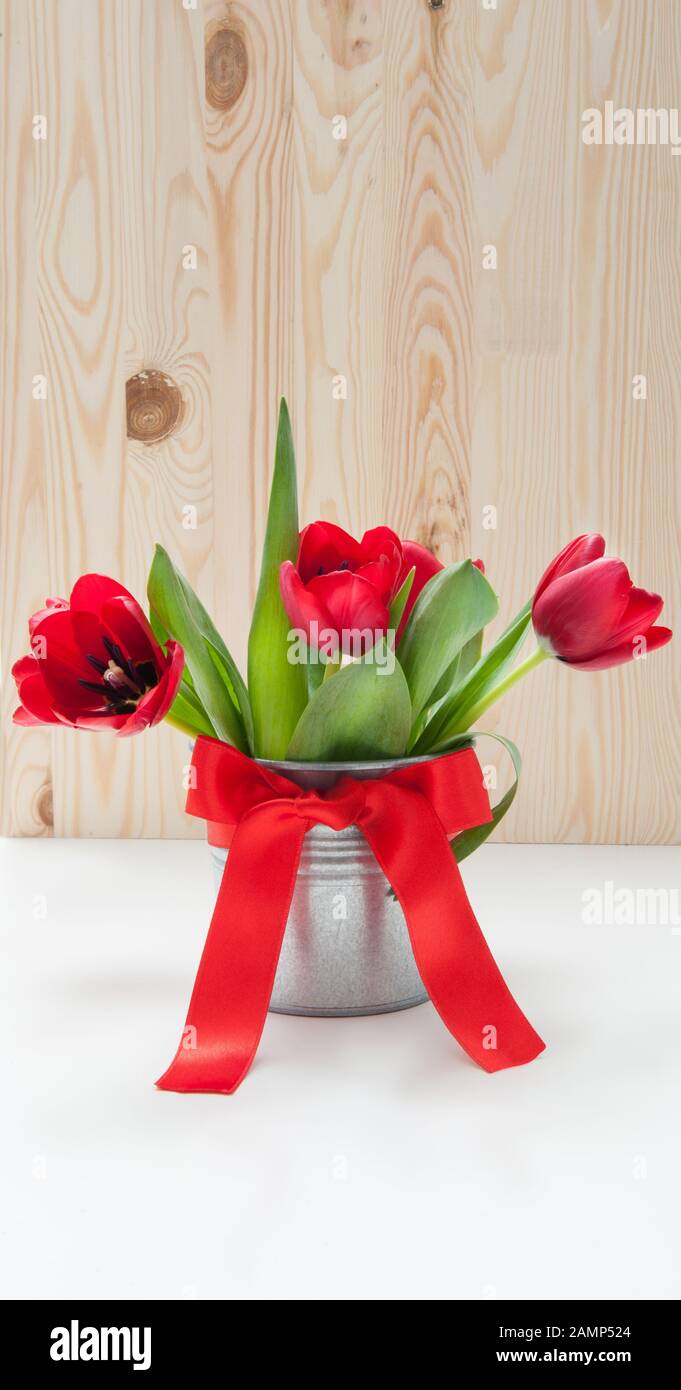 Bouquet de tulipes dans un seau en fer avec un noeud rouge Banque D'Images