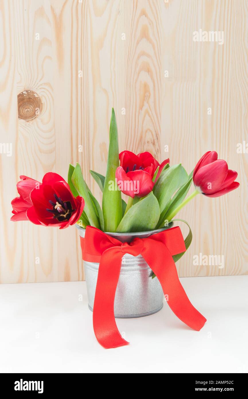 Bouquet de tulipes dans un seau en fer avec un noeud rouge Banque D'Images