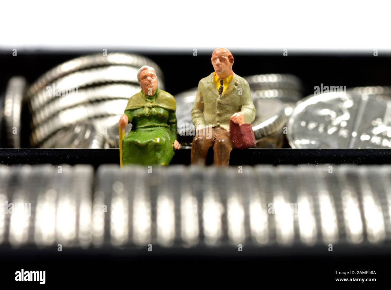 Miniatures, couple retraité assis sur l'argent,cash,pièces,concept Banque D'Images