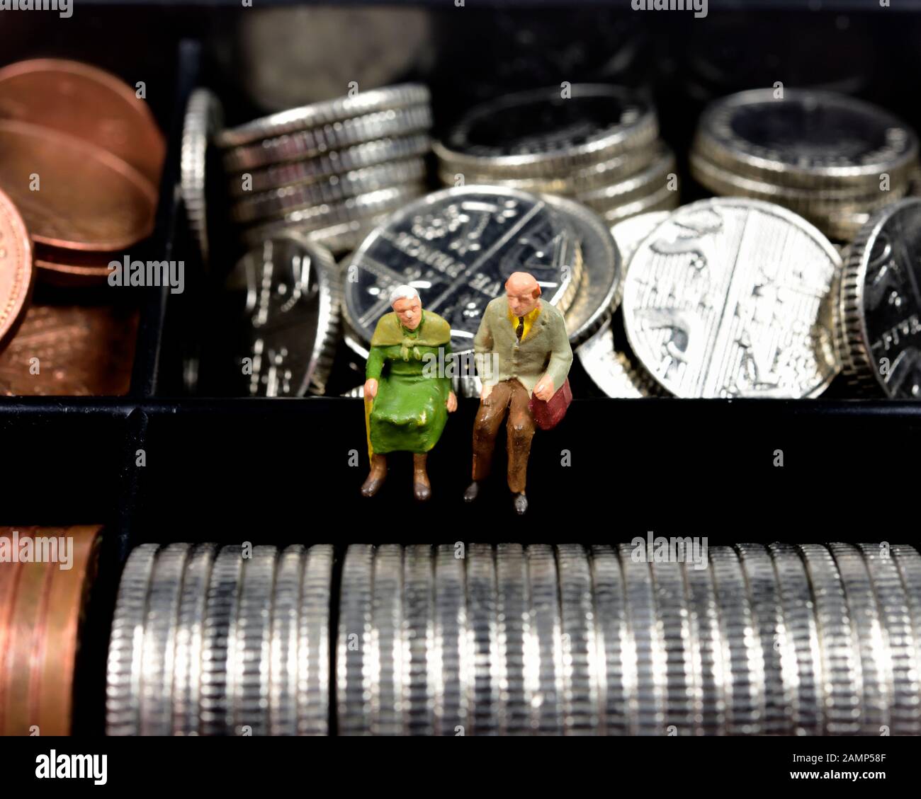 Miniatures, couple retraité assis sur l'argent,cash,pièces,concept Banque D'Images