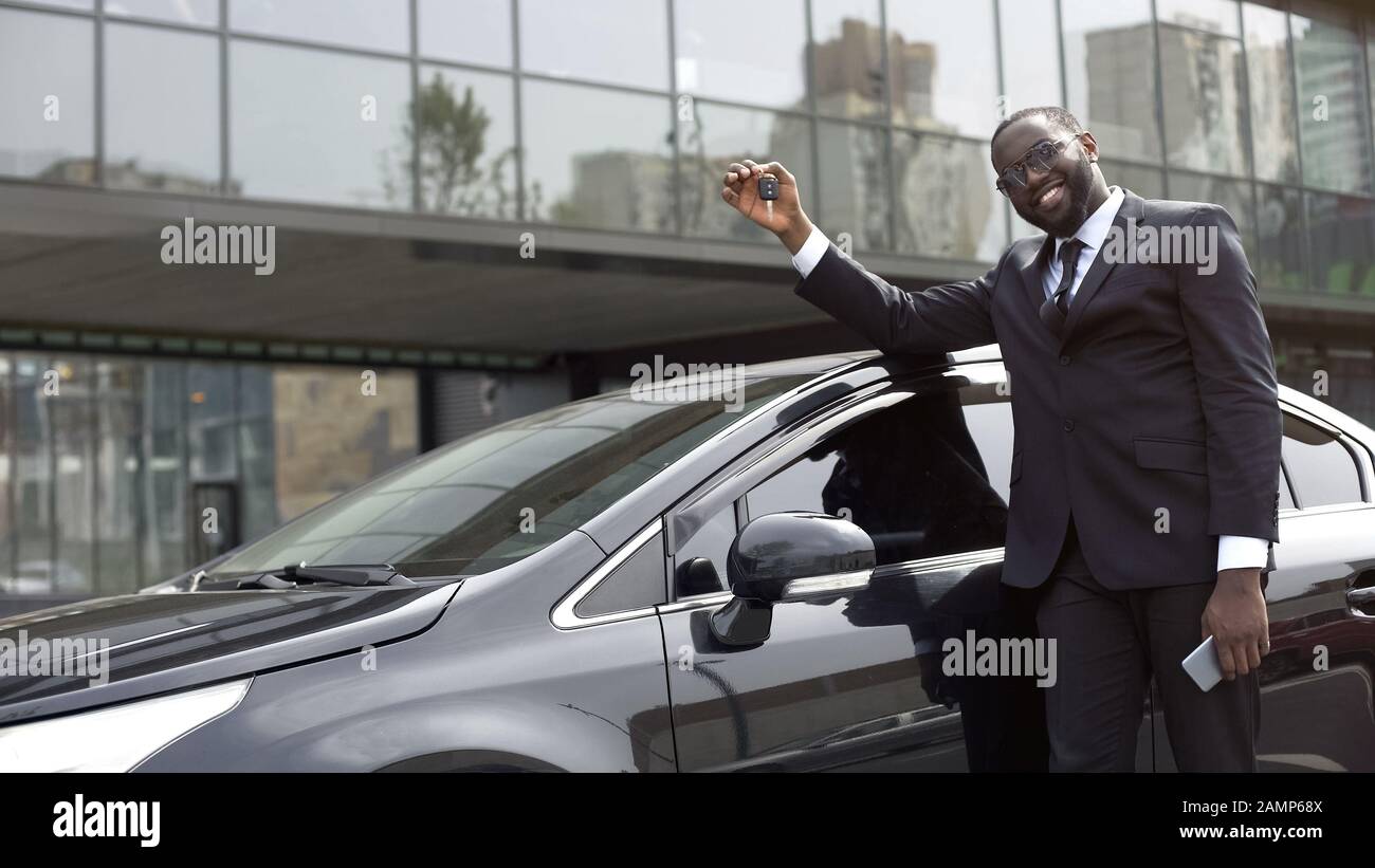 Enchanté homme africain américain montrant la clé de la nouvelle voiture de luxe, les rêves deviennent réalité Banque D'Images