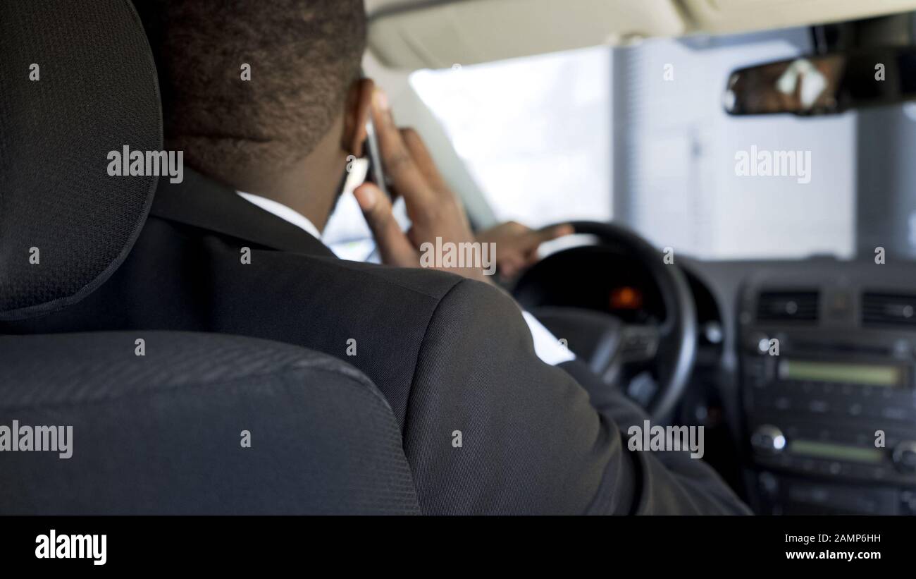 Homme afro-américain communiquant par smartphone en voiture, vue arrière Banque D'Images