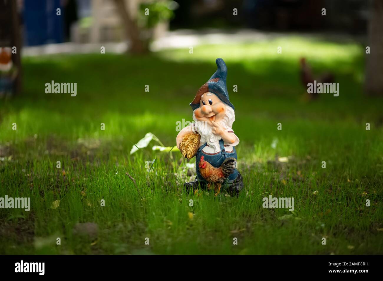 Gnome de jardin avec un coq sur la pelouse Banque D'Images