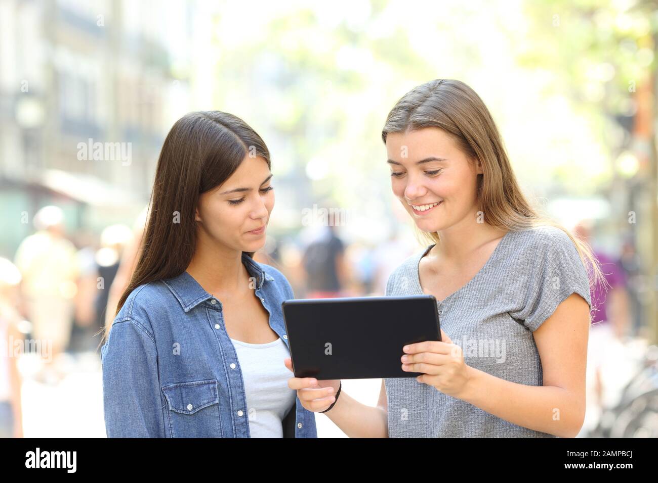 Deux amis regardant des contenus en ligne sur tablette dans la rue Banque D'Images