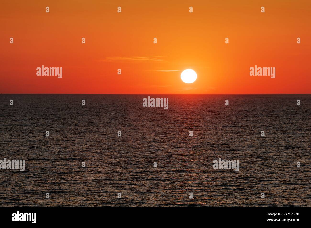 Coucher de soleil dans l'océan avec grand soleil crépuscule vagues douces et ciel nuageux rouge. Fond du lever du soleil de la mer. Photographie de paysage Banque D'Images