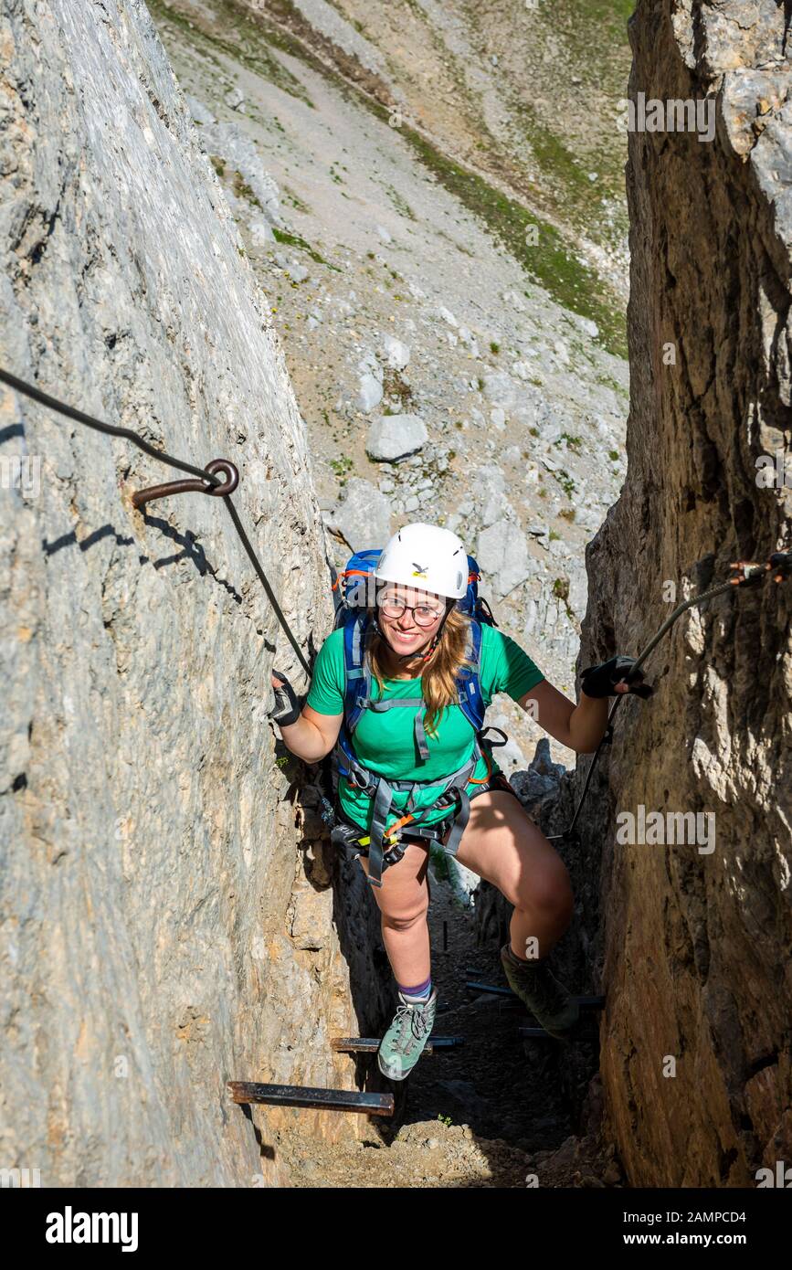 Grimpeur en riant la jeune femme avec un casque d'escalade sur une sécurisé via ferrata, Mittenwald via ferrata, Karwendel Mountains, Mittenwald, Allemagne Banque D'Images
