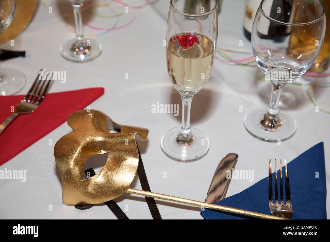 Masque de balle en mascarade doré sur une table de dîner. Carnaval Venetian Eye Mask, accessoire de robe fantaisie, boule de costume de fête de Carnaval. Banque D'Images