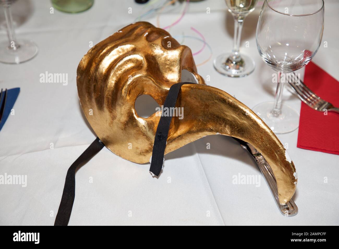 Masque de balle en mascarade doré sur une table de dîner. Carnaval Venetian Eye Mask, accessoire de robe fantaisie, boule de costume de fête de Carnaval. Banque D'Images