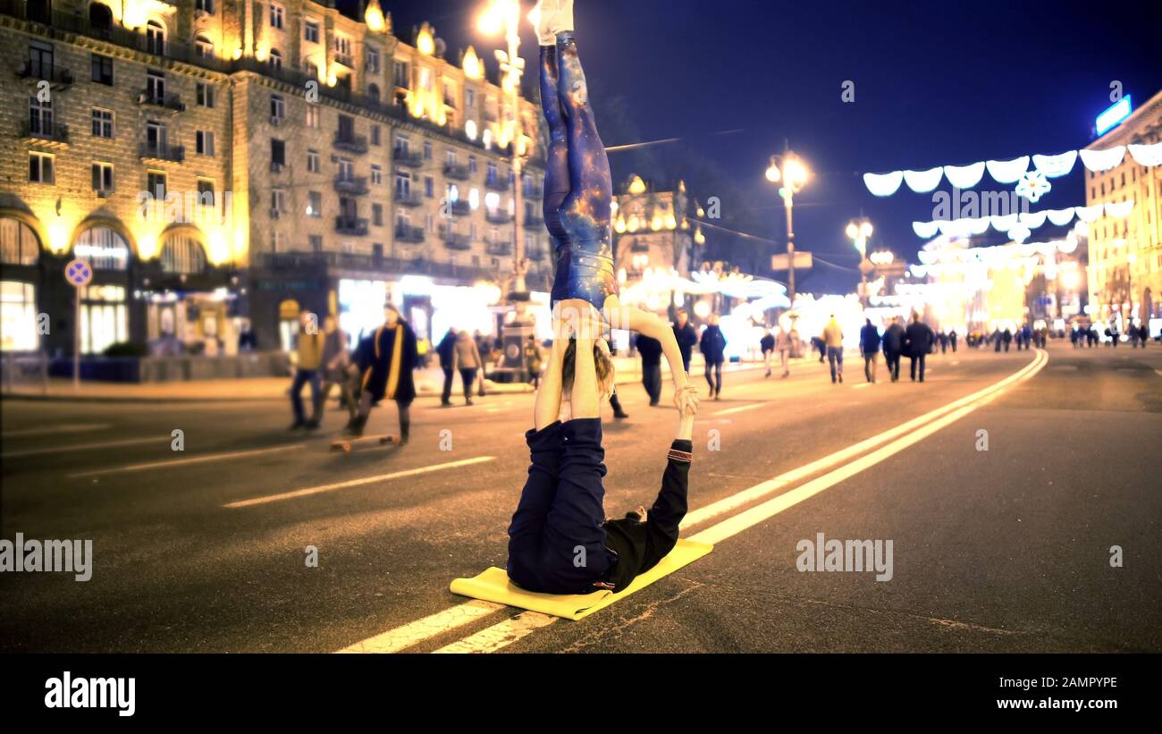 Femme et homme faisant des cascades acrobatiques dans le centre-ville, l'heure du soir, passe-temps extrême Banque D'Images