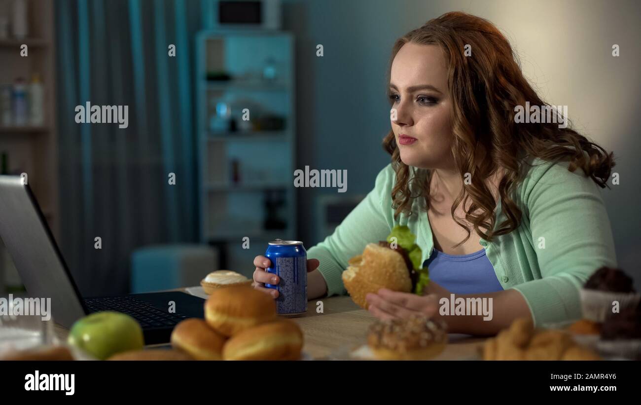 FAT fille manger de la nourriture de la jonque tout en regardant l'opéra de  savon sur ordinateur portable, le style de vie passif Photo Stock - Alamy