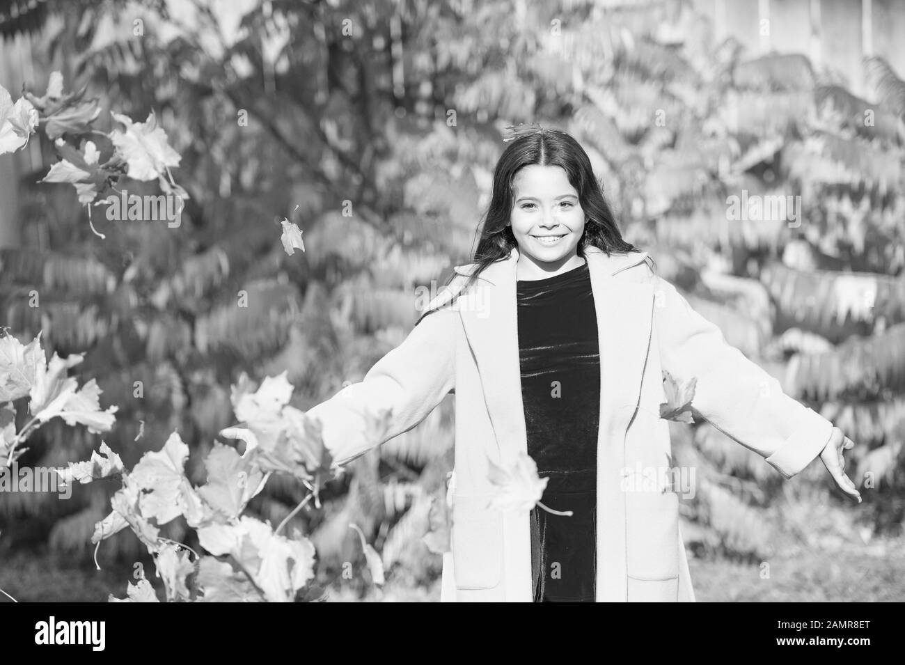 L'automne chaud. La chute des feuilles. Fille élégant manteau en automne balade en automne parc. Les feuilles tombées. Nature de l'automne. Petit enfant heureux à l'extérieur jouer avec des feuilles. Girl walking in park journée ensoleillée. Profitez de moment. Banque D'Images