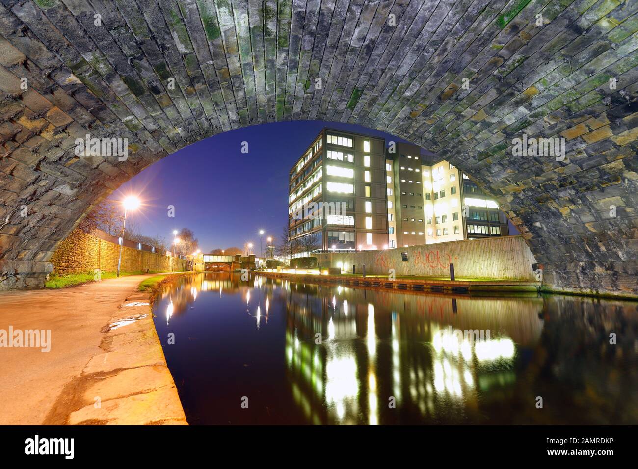 Sous un pont ferroviaire disutilisé à côté du Leeds au canal de Liverpool. N° 1 les bureaux de Whitehall reflètent dans le canal Banque D'Images