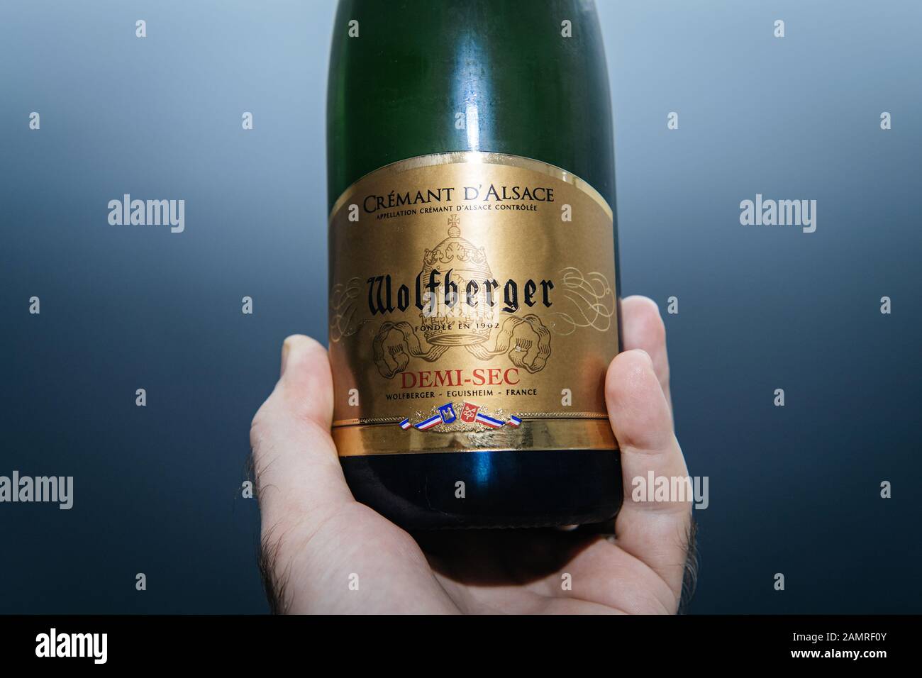 Paris, France - 1 janvier 2020: Bouteille de vin mousseux Cremant d'Alsace Wolfberger Demi-sec d'homme sur fond bleu Banque D'Images