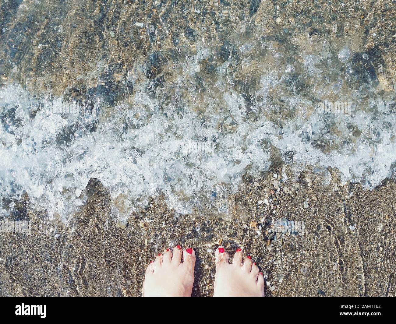 Gros plan sur les pieds de la femme debout dans l'océan surf, Malaga, Espagne Banque D'Images