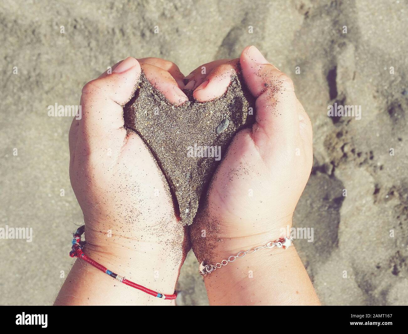 Femme debout sur la plage tenant une poignée de sable en forme de coeur, Malaga, Espagne Banque D'Images