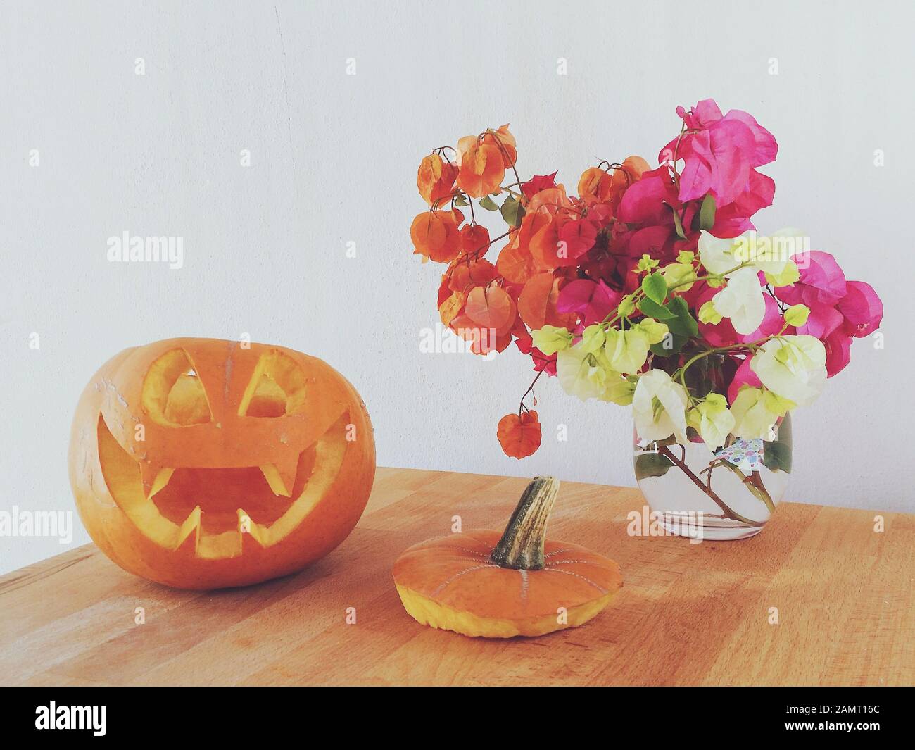 Jack-o-lanterne à côté d'un vase de fleurs sur une table Banque D'Images