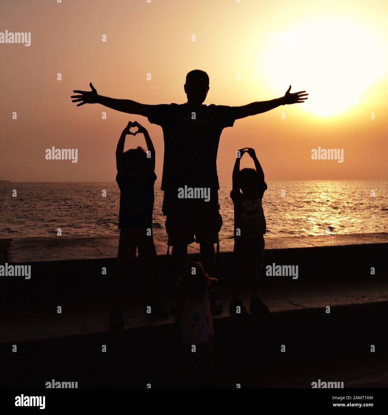 Père et deux enfants se tenant sur la plage en faisant des gestes de la main en forme de coeur, Espagne Banque D'Images