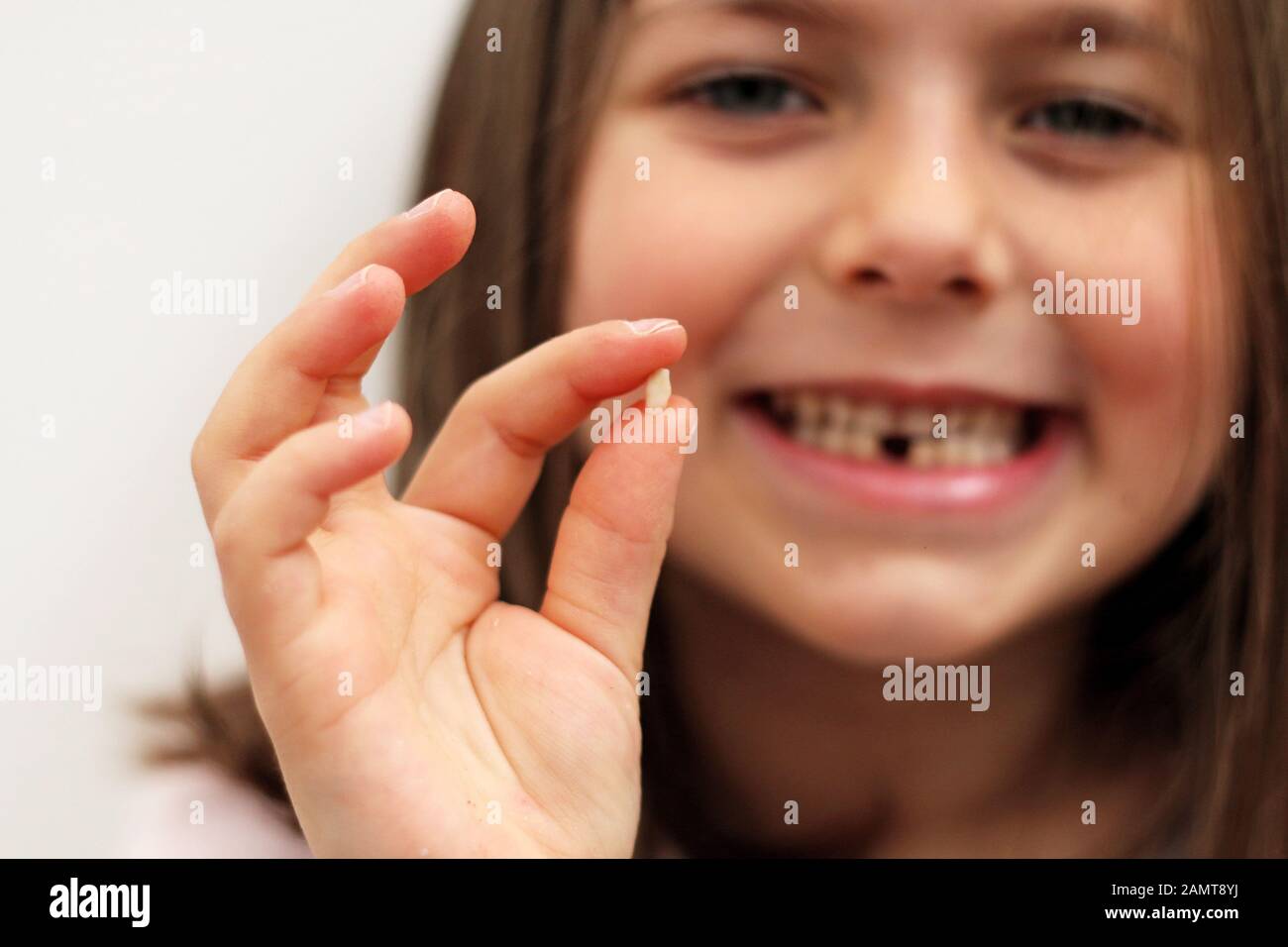 Portrait d'une jeune fille à denture à fente qui tient sa première dent de lait tombée Banque D'Images