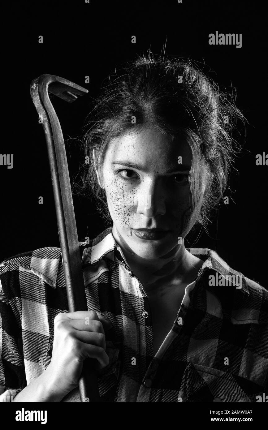Jeune femme sérieuse sanglante avec crowbar dans le noir à la caméra à image monochrome Banque D'Images