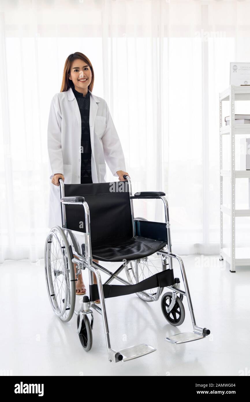 Portrait of female doctor holding medical fauteuil roulant professionnel dans la salle d'examen clinique de l'hôpital Banque D'Images