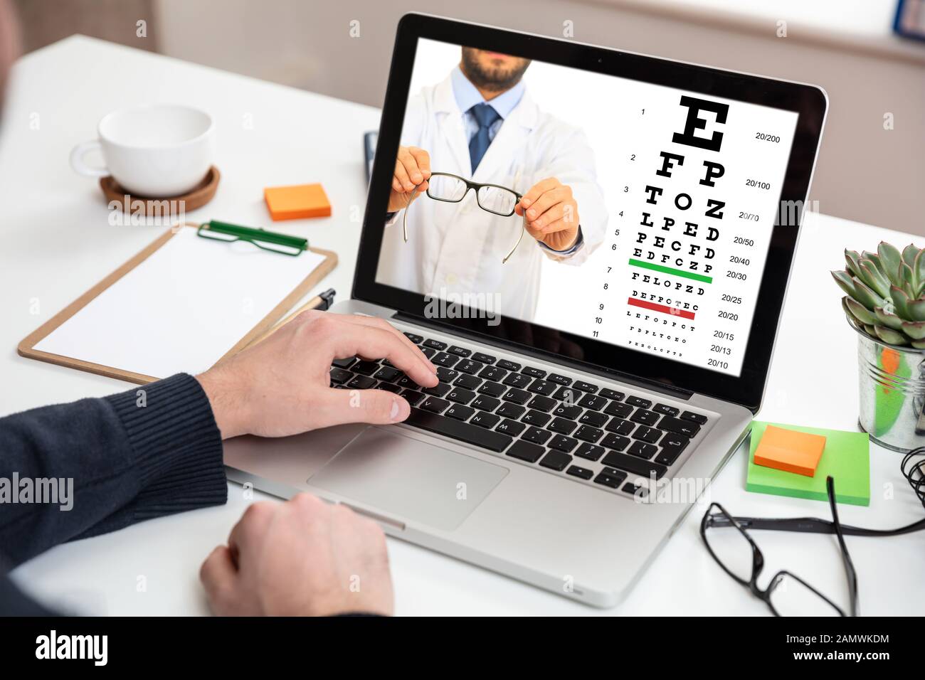 Vue, concept de test en ligne de vision de l'œil. Homme offrant des lunettes sur un écran d'ordinateur portable, bureau arrière-plan Banque D'Images