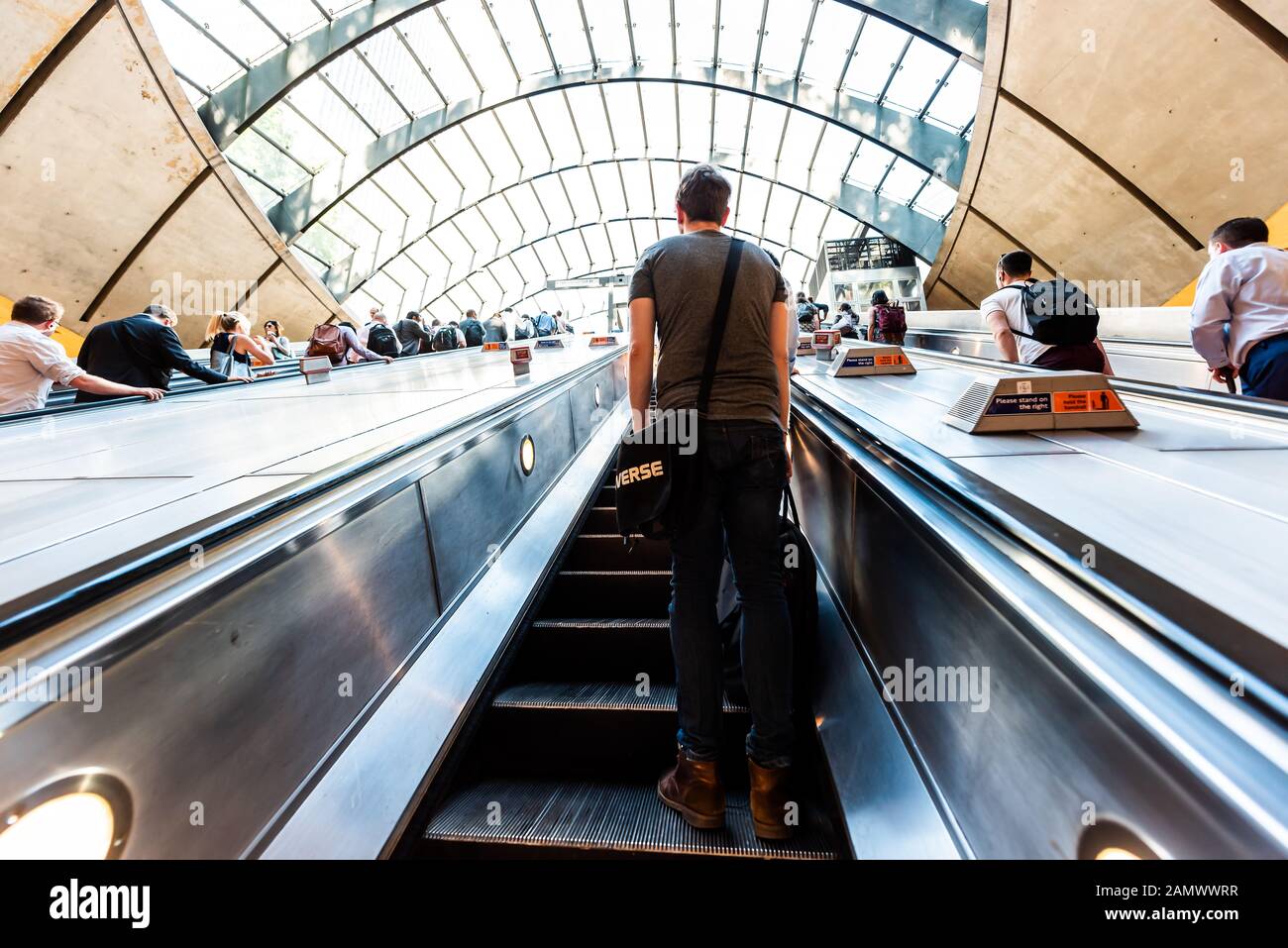 Londres, Royaume-Uni - 26 juin 2018 : les voyageurs qui voyagent par des escaliers mécaniques en métro pendant le trajet du matin à Canary Wharf avec architecture moderne Banque D'Images