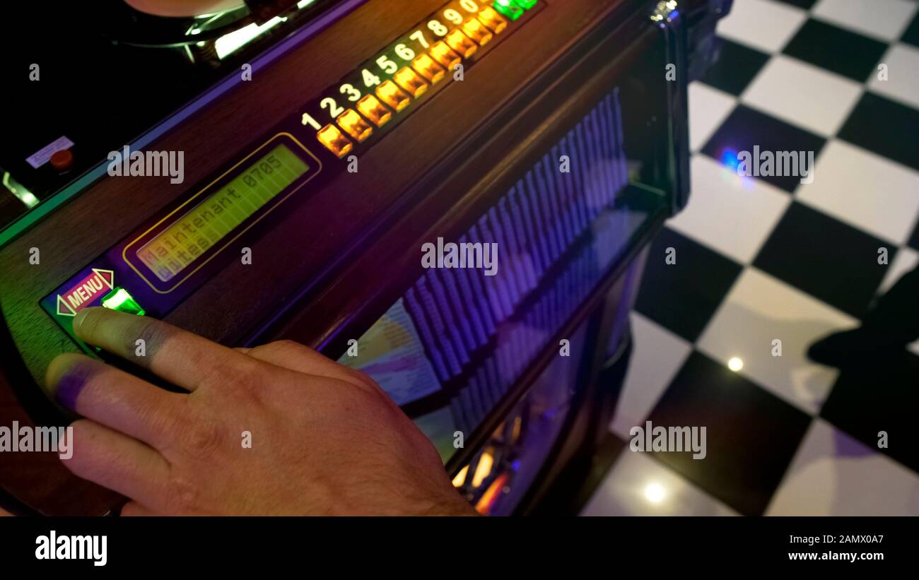 Visiteur de bar masculin choisir la chanson à jouer sur le juke-box avec une grande variété de disques Banque D'Images