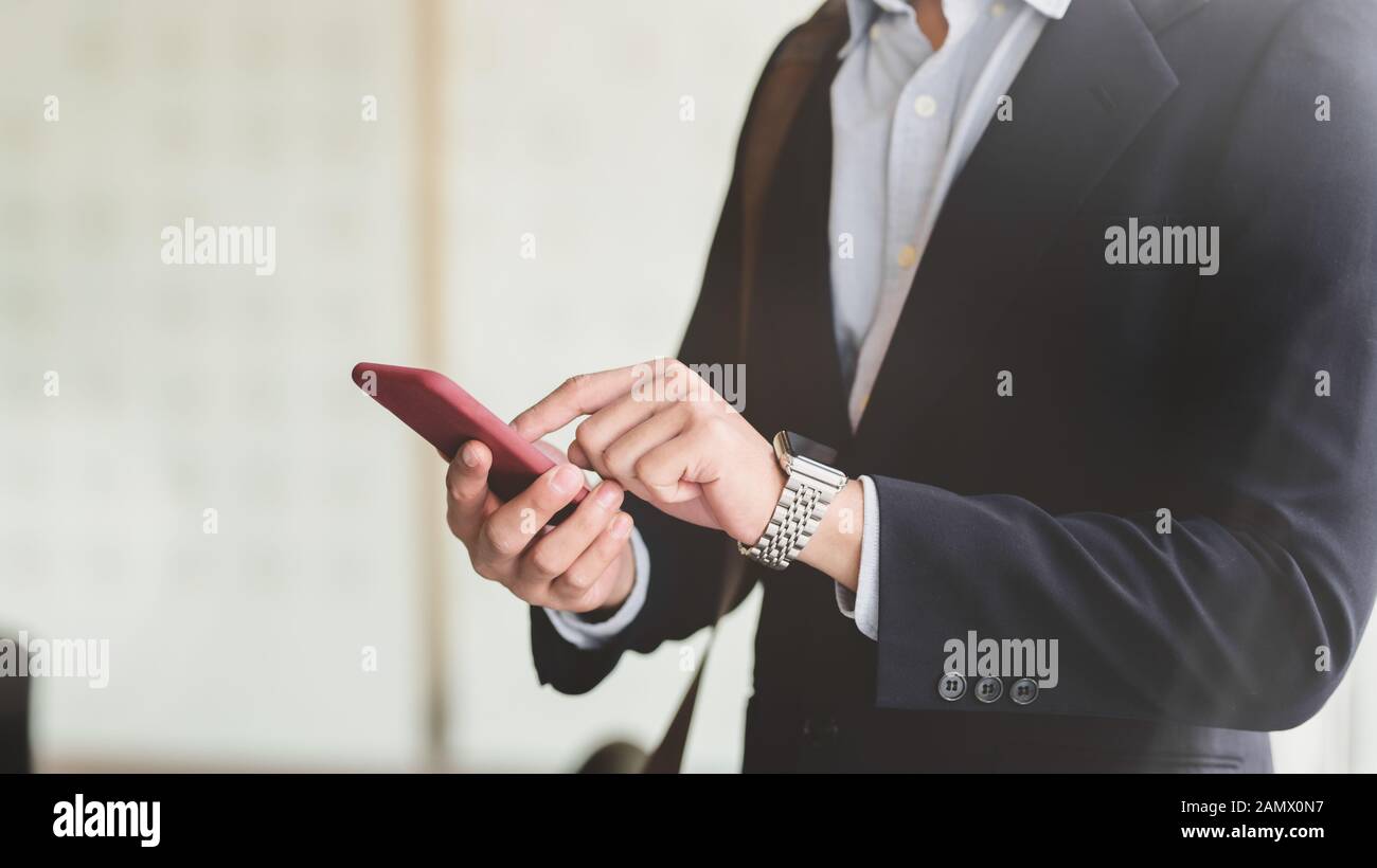 Close up of young businessman touching professionnel sur smartphone dans l'arrière-plan flou salle de réunion Banque D'Images
