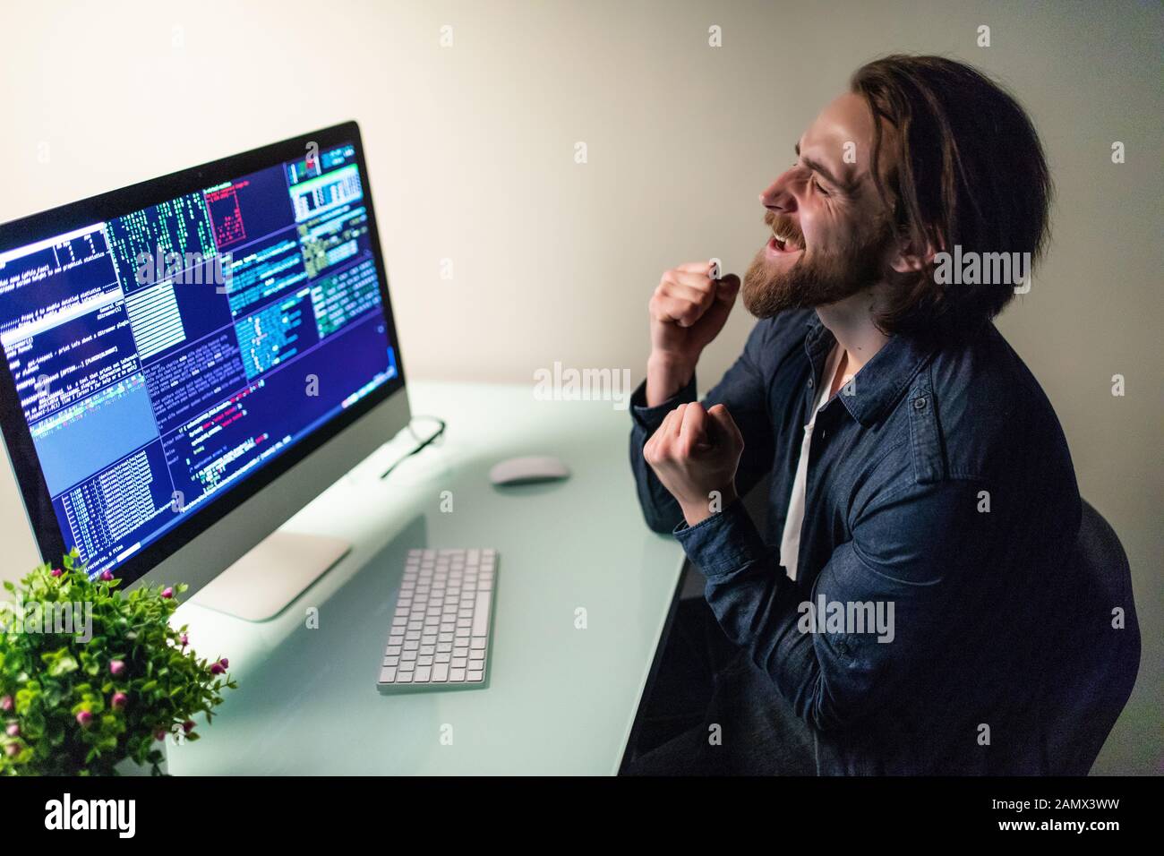 Heureux l'homme programmer travaillant sur l'ordinateur avec le geste de gain Banque D'Images