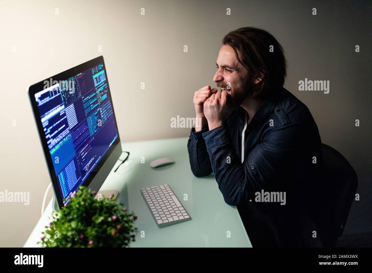 Heureux l'homme programmer travaillant sur l'ordinateur avec le geste de gain Banque D'Images