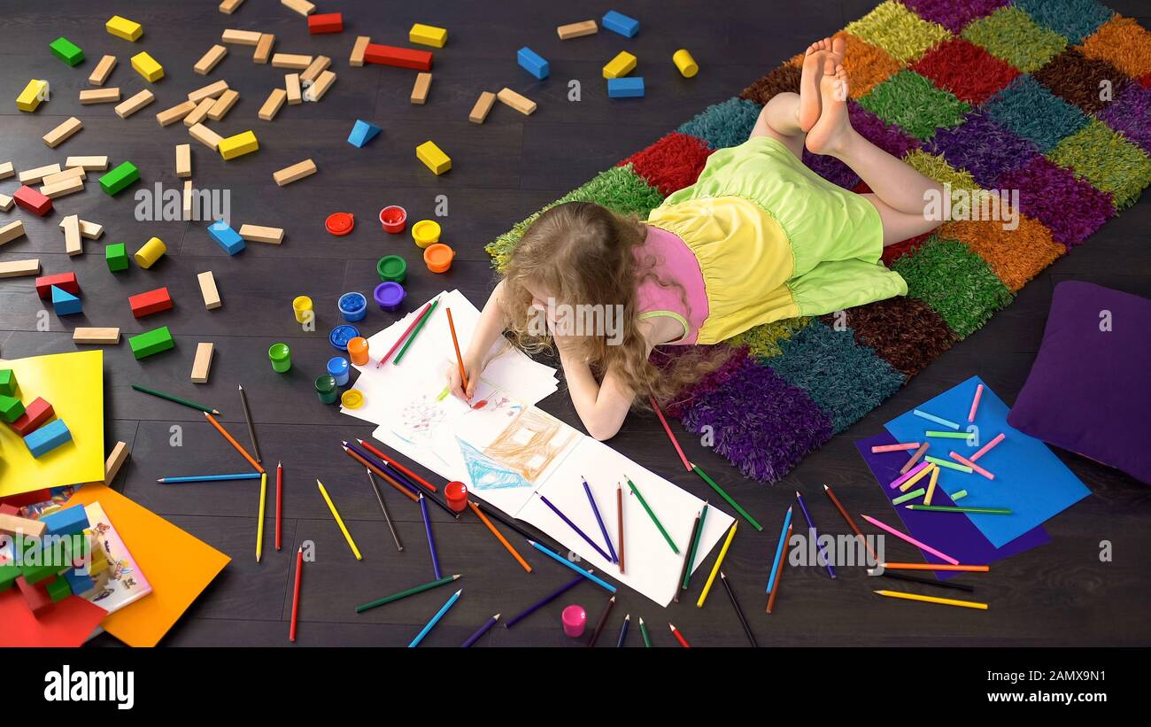 Jolie fille préscolaire dessin avec crayon de couleur sur papier, couché sur le sol Banque D'Images