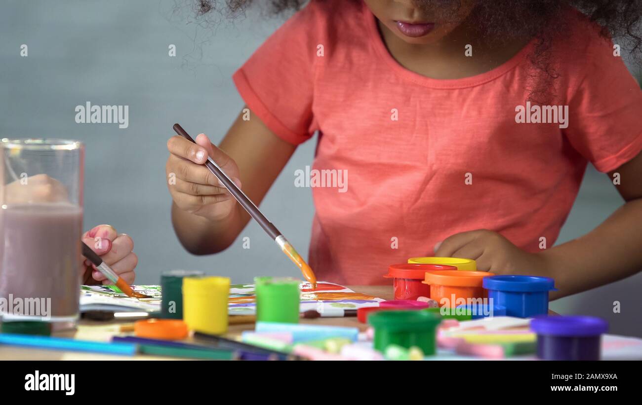Petite fille afro-américaine peint une photo au club d'art, éducation préscolaire Banque D'Images