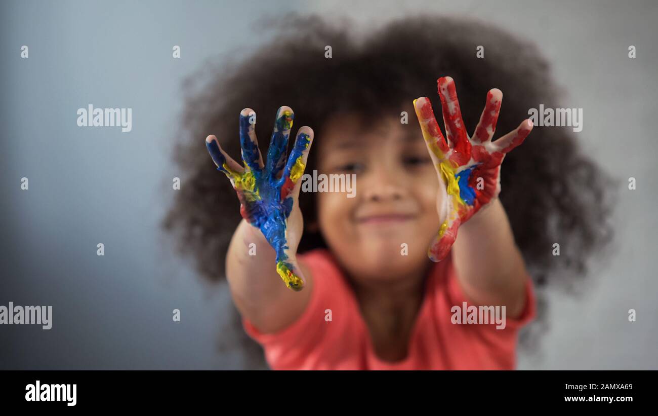 Joyeux enfant féminin africain qui s'amuse et montre des palmiers peints dans l'appareil photo Banque D'Images