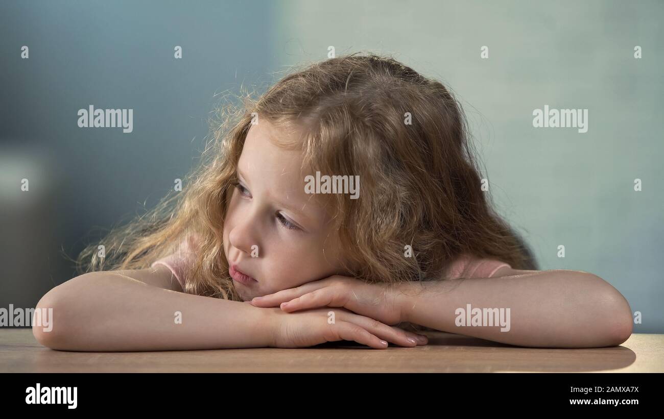 Petite fille assise à la table et allant pleurer, abus d'enfants, solitude Banque D'Images