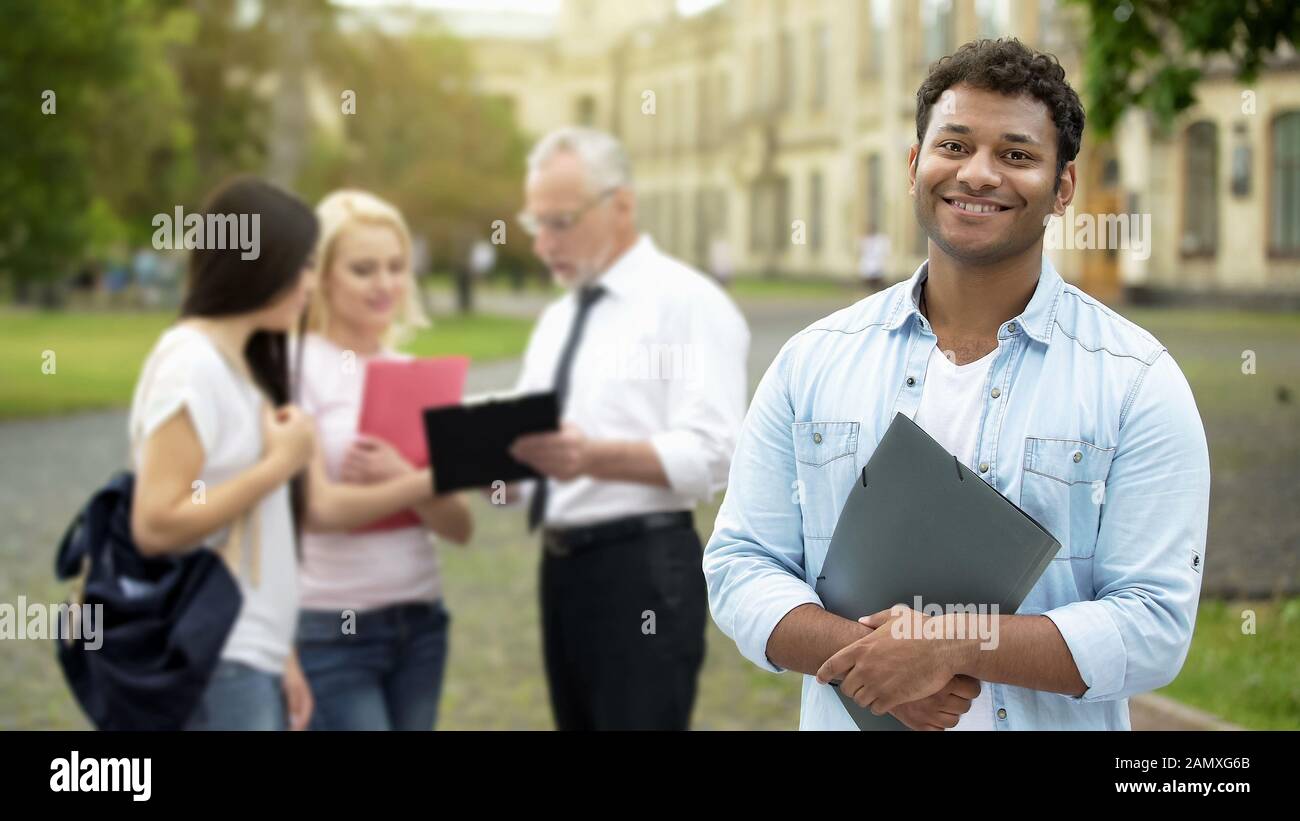Un étudiant hispanique heureux se tenant près de l'université et souriant à l'appareil photo, l'éducation Banque D'Images