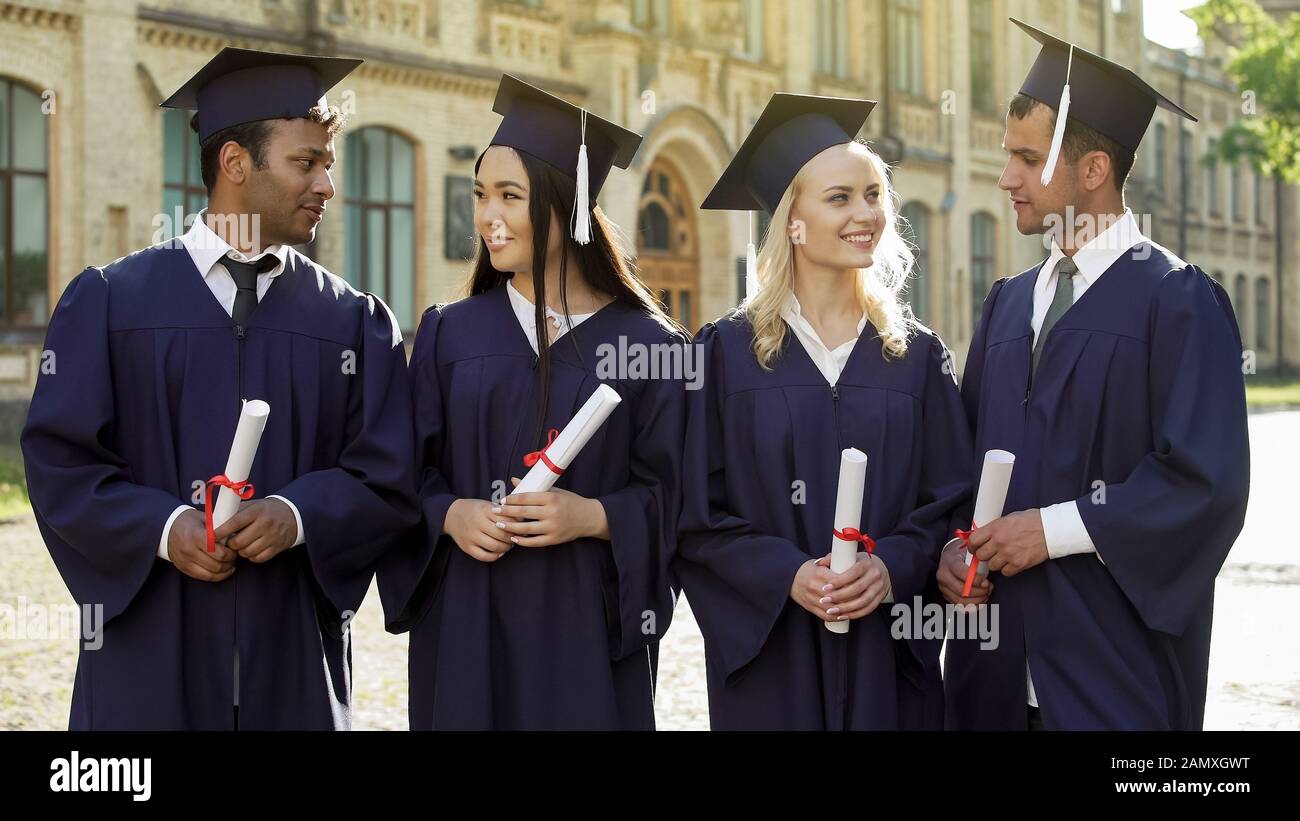 Des étudiants de deuxième cycle et de bonne humeur dans les domaines universitaires parlent entre eux, le succès Banque D'Images