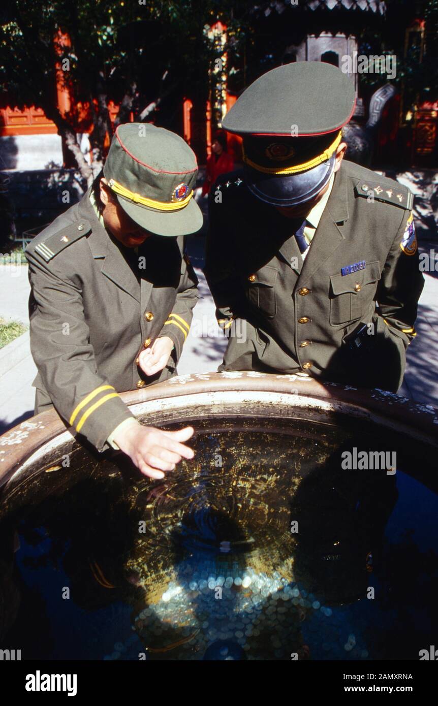 Zwei Soldaten werfen Münzen dans einen Wunschbrunnen à Pékin, Chine UM 1990. Deux soldats qui donnent des pièces dans un puits de souhait à Beijing, en Chine vers 1990. Banque D'Images